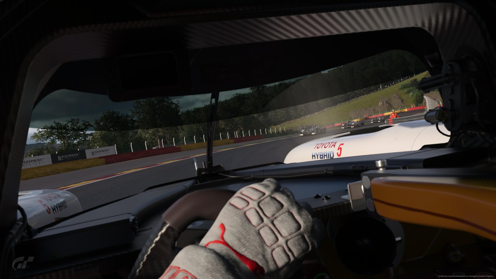 GT7 cockpit POV — Toyota Hybrid side-by-side with a teammate at Spa, driver's gloved hand on the wheel